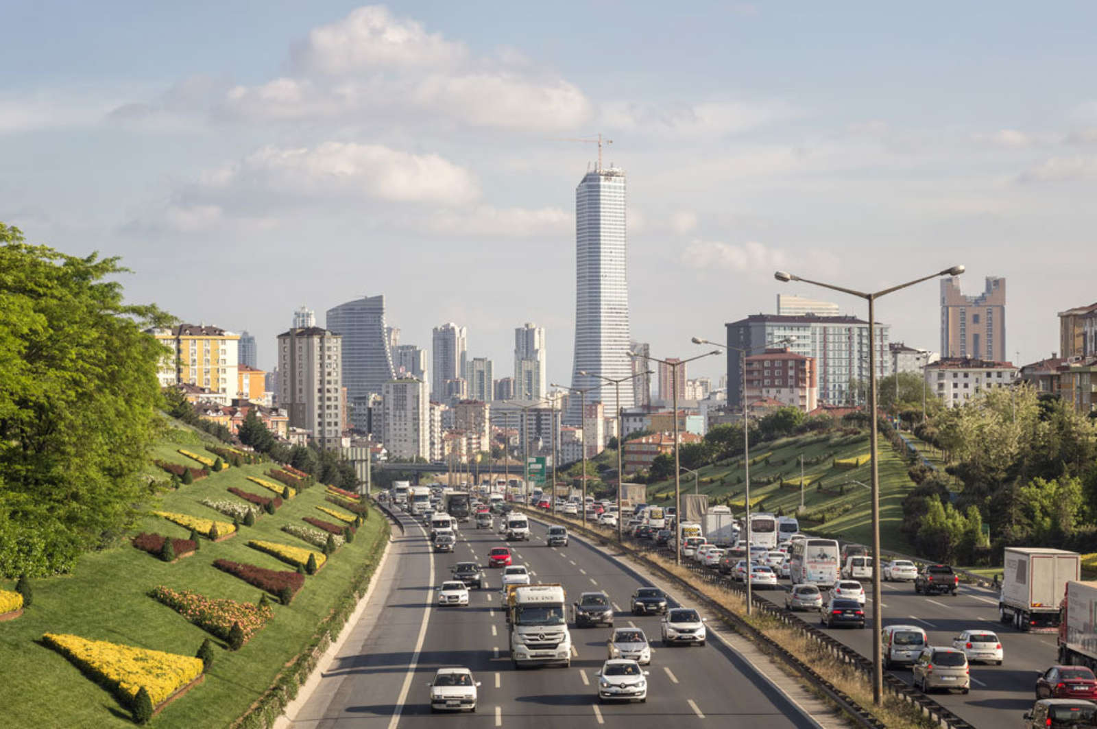 Traffic on a multi-lane urban motorway in Istanbul, with the city skyline in the background.