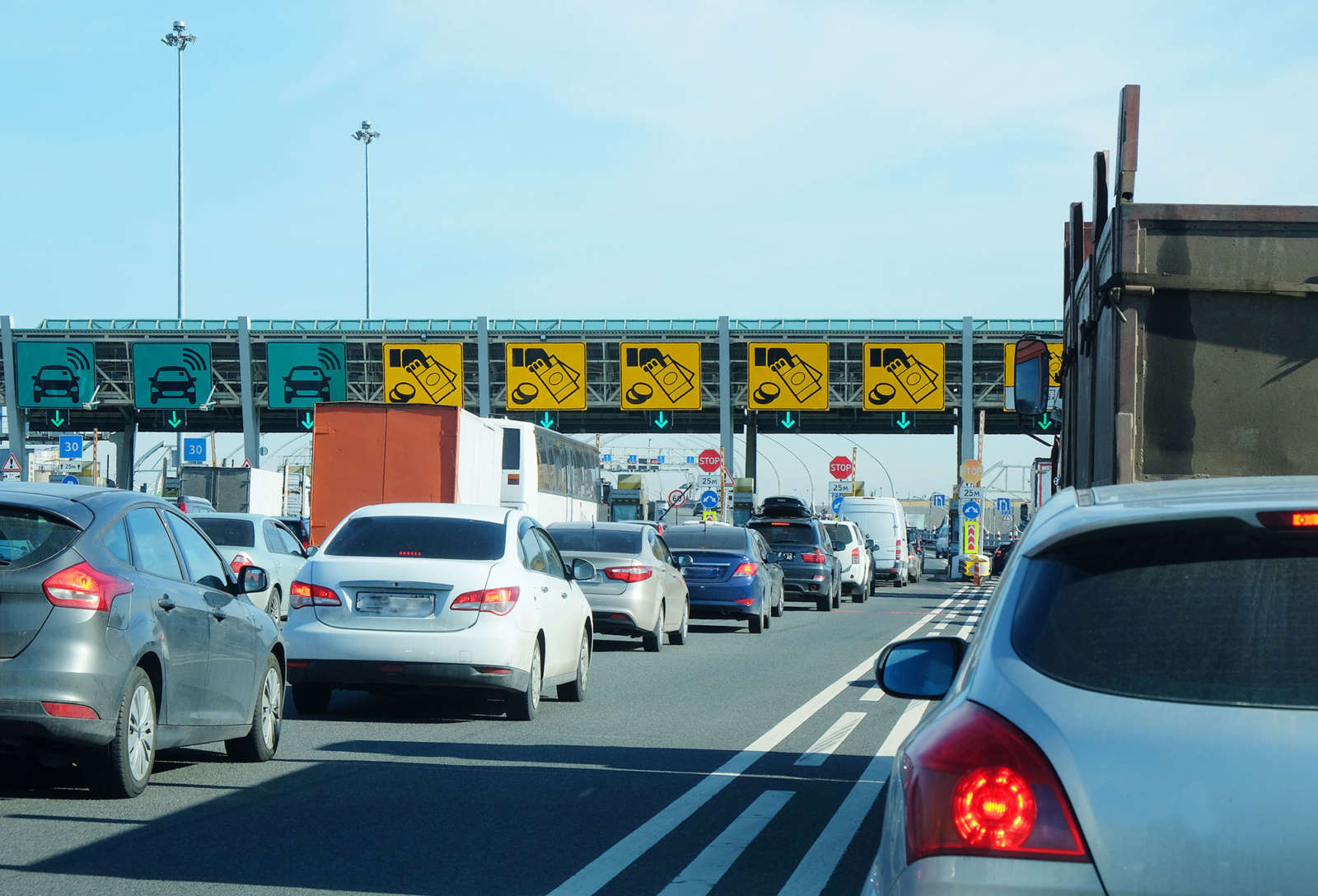 Cars and trucks queuing at a toll gate with overhead payment lane signs.