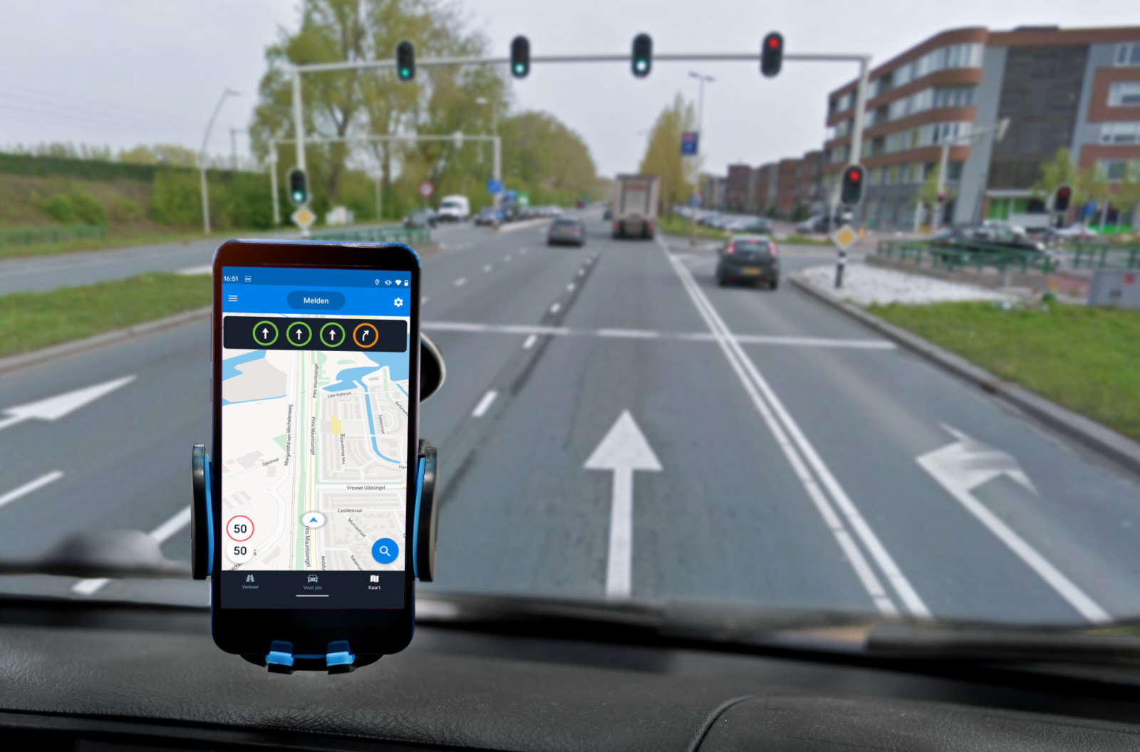Car dashboard view with a smartphone in a mount showing traffic light signal information in a navigation app