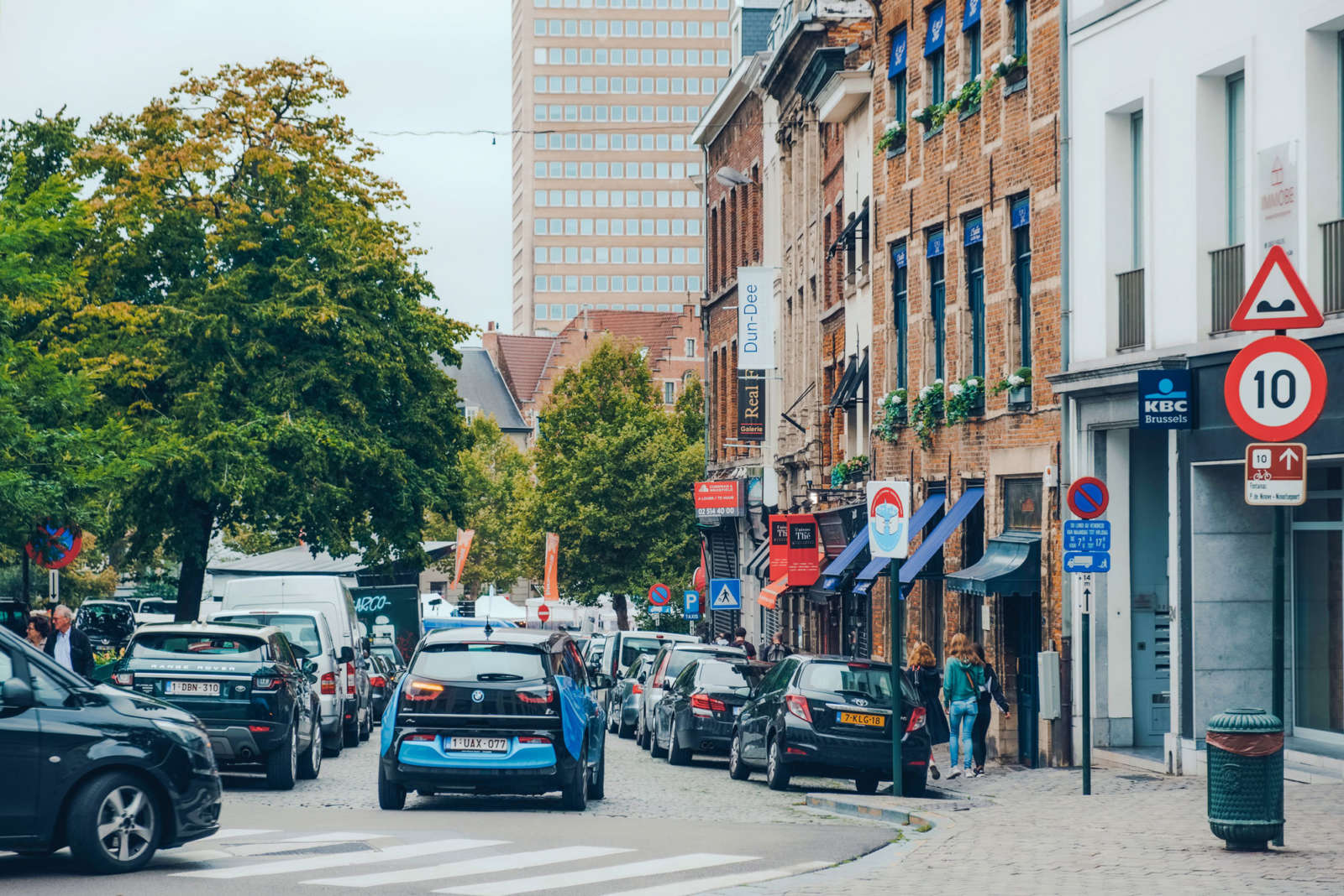 Busy Brussels street with parked cars along the kerb and passing traffic