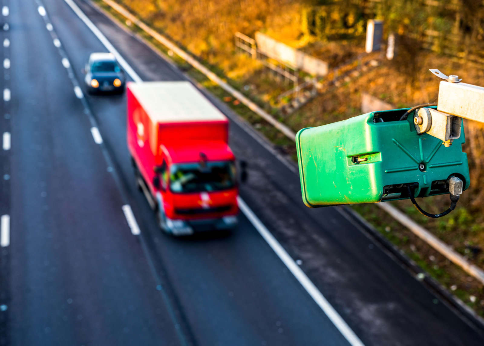 ANPR camera mounted above a motorway with a truck and car passing underneath.