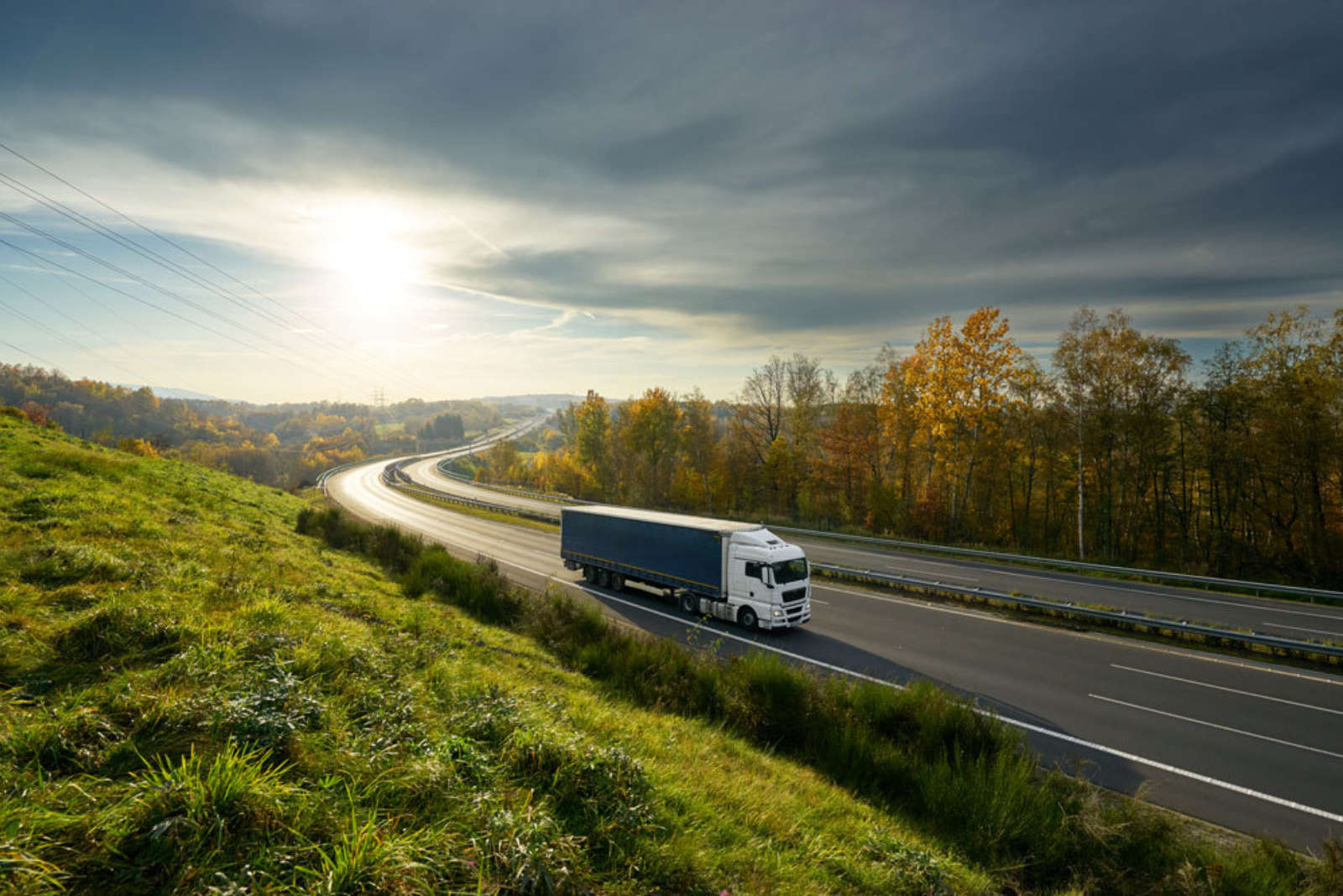 Single truck driving on an empty winding highway in low evening sunlight